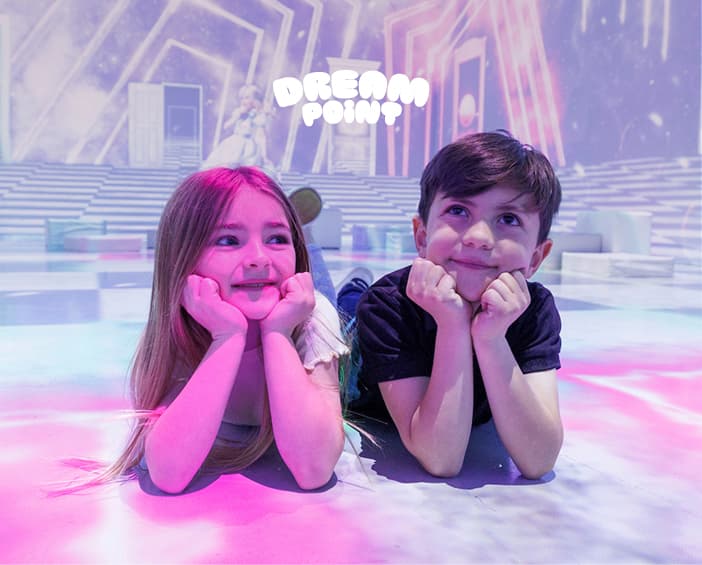 Two children smiling inside the glowing Dream Point experience